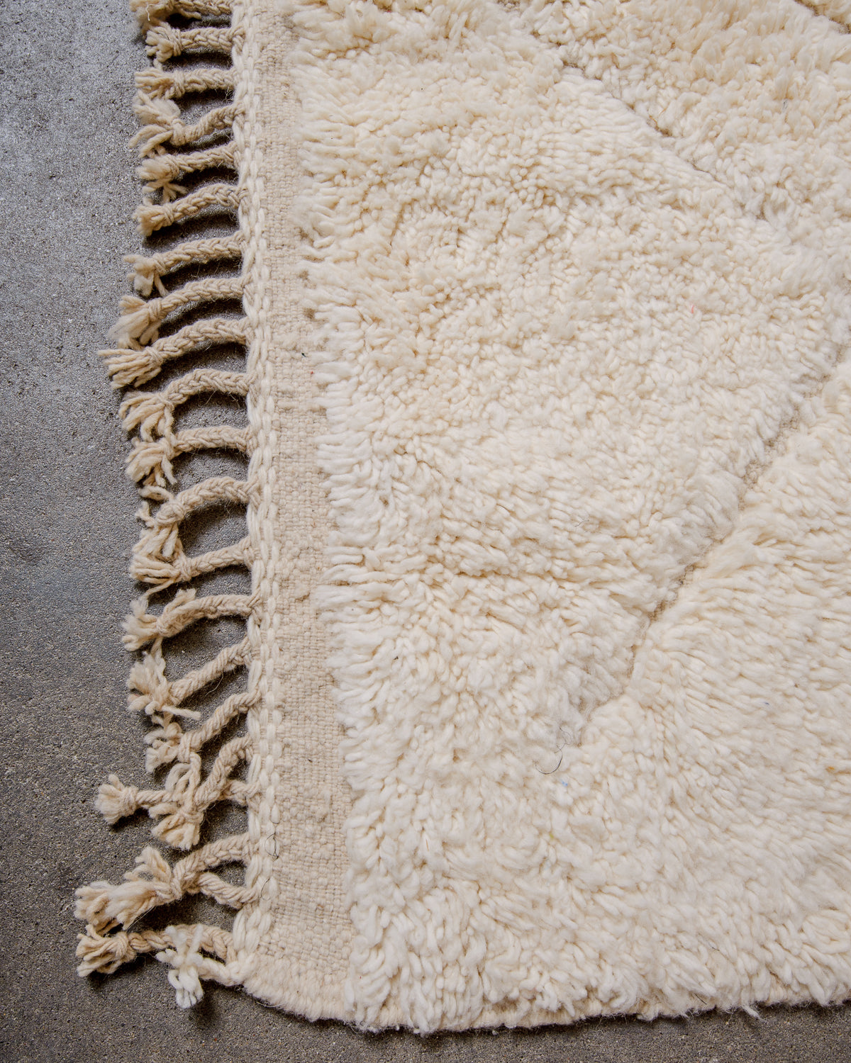 Corner of beniourain rug with tightly woven end and natural wool tassels.
